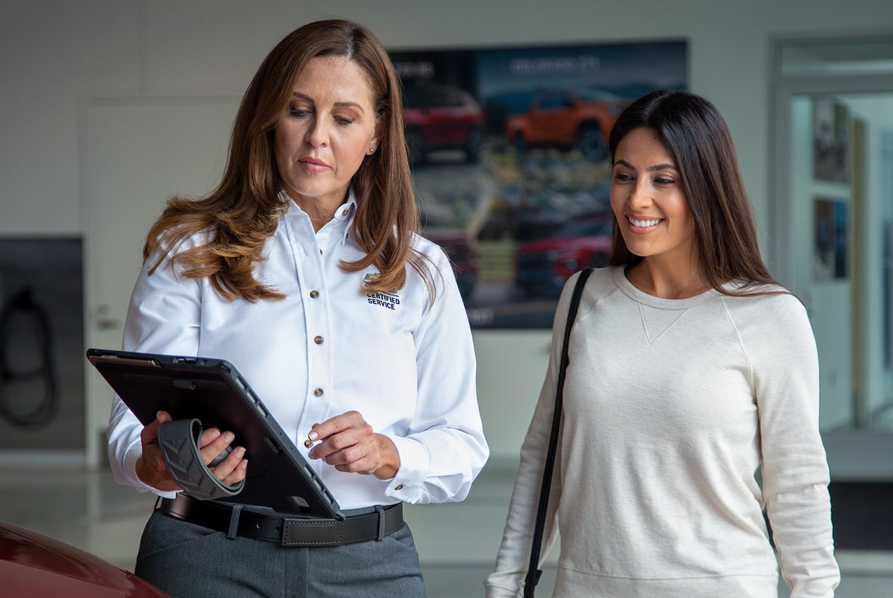 A Vehicle Dealer Employee Holding a Tablet While Talking to a Customer