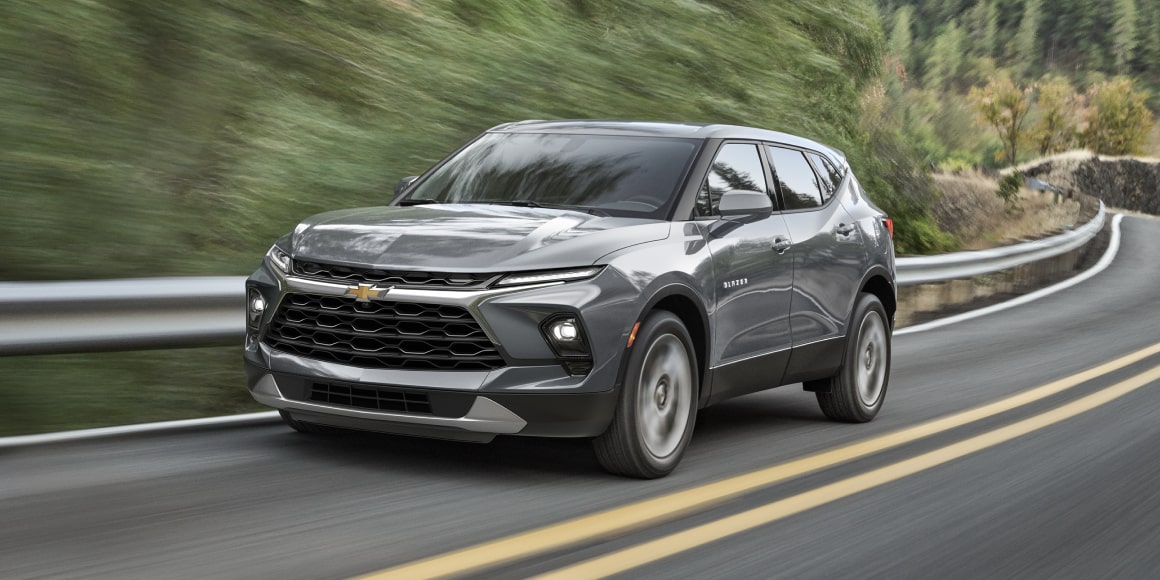 Gray 2025 Chevy Blazer Driving Swiftly on a Treelined Road