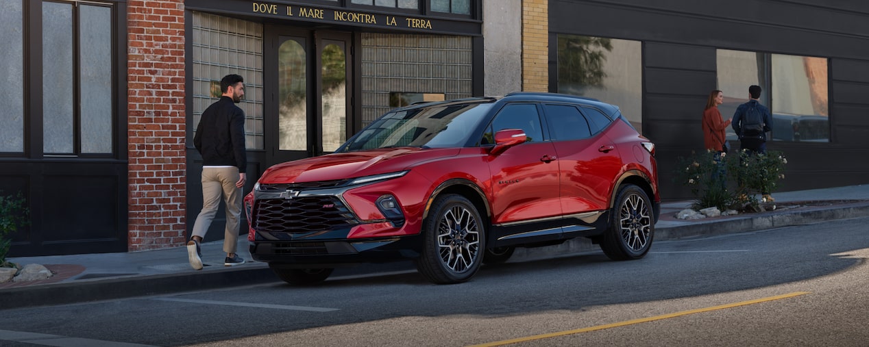 Man Walking Toward His 2025 Red Chevy Blazer Parked at a Shop