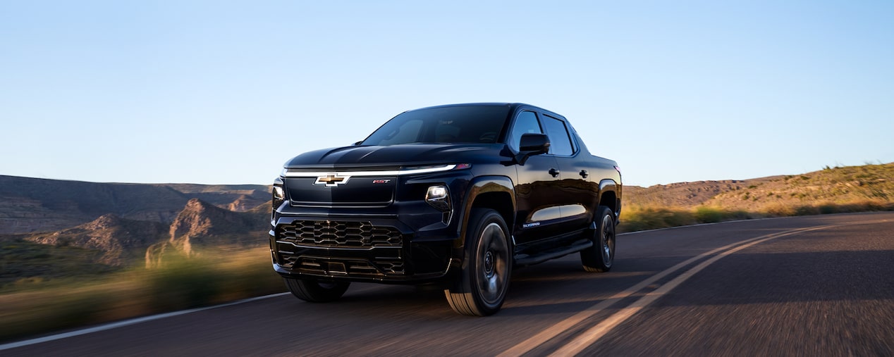 Silverado EV de color Negro circulando por un camino de curvas al atardecer