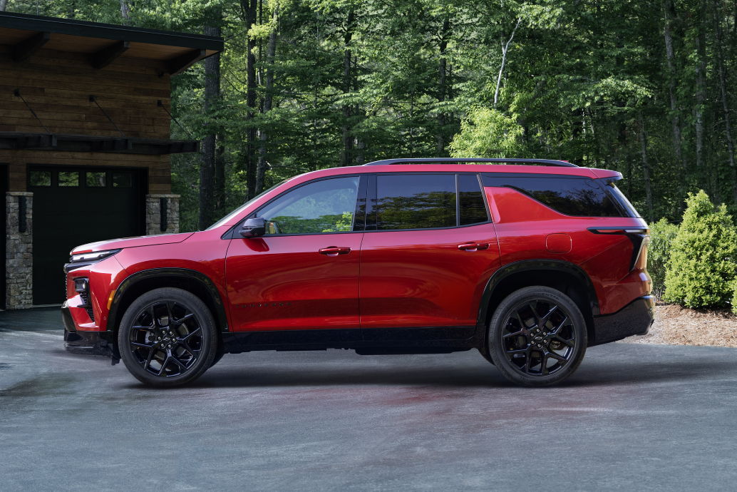 Lado del conductor de una Chevy Traverse 2024 estacionada en la entrada de una cabaña