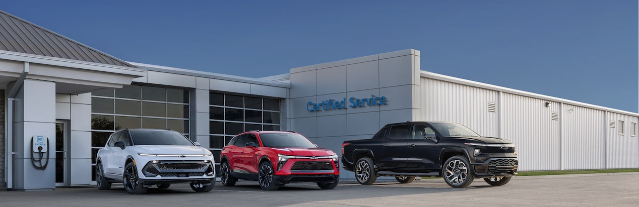 Three Chevy Vehicles Parked in Front of a Chevy Certified Service Garage