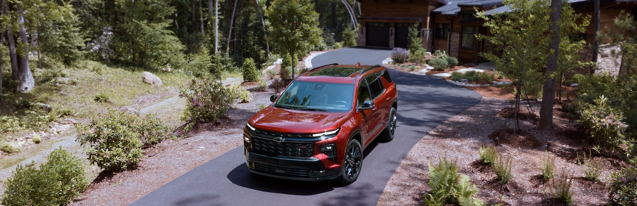 A Chevy SUV Parked outside of a home surrounded by trees