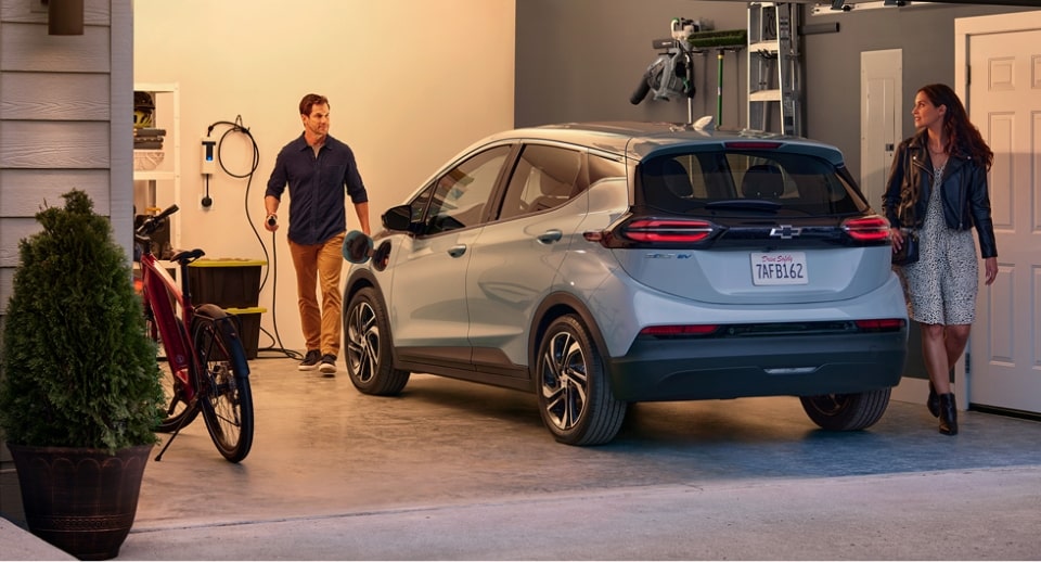 Una pareja de pie en su garaje cerca de su Chevrolet Bolt EV