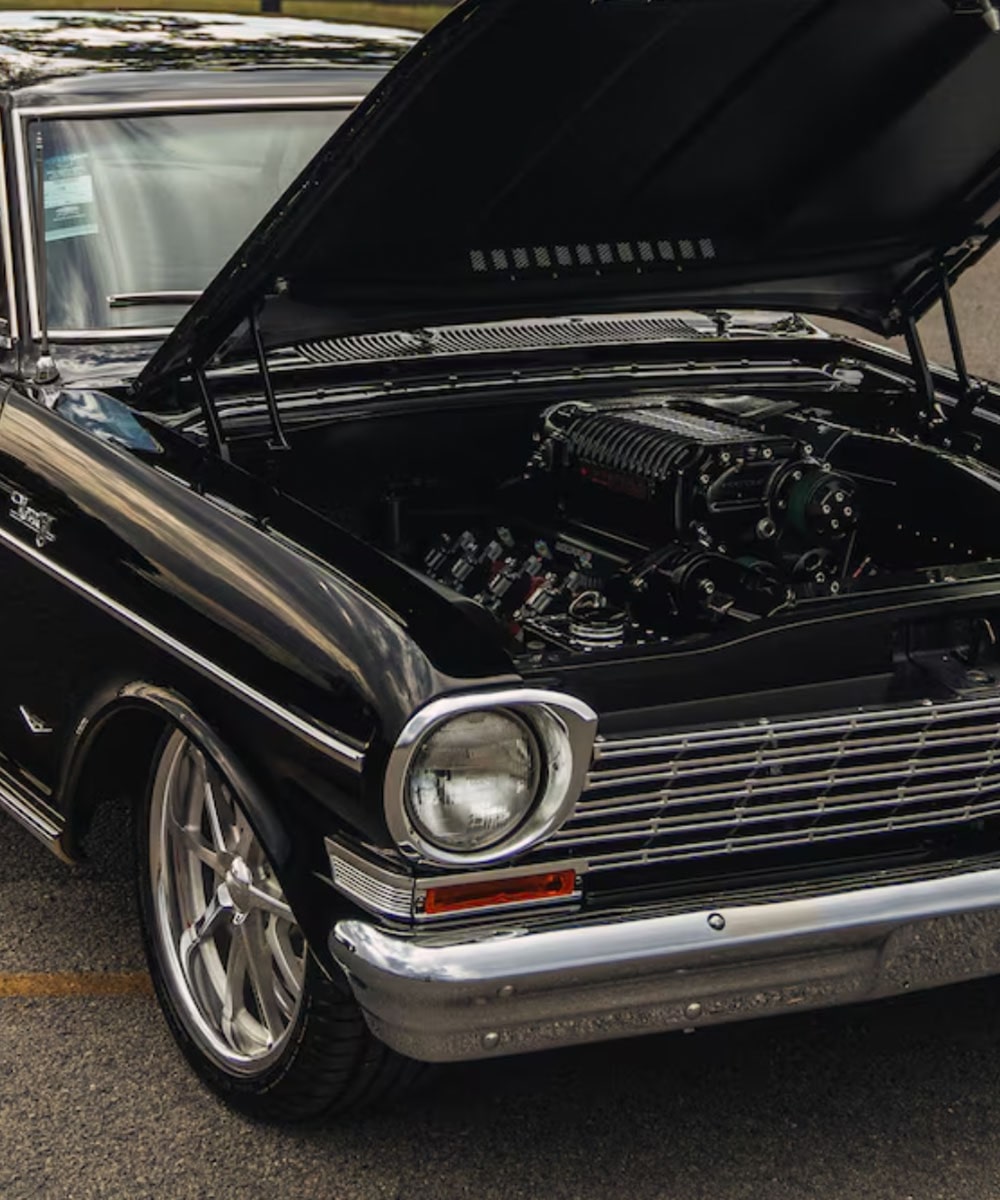 Front Three Quarters View of a Classic Black GM Car with the Hood Open and Engine Visible