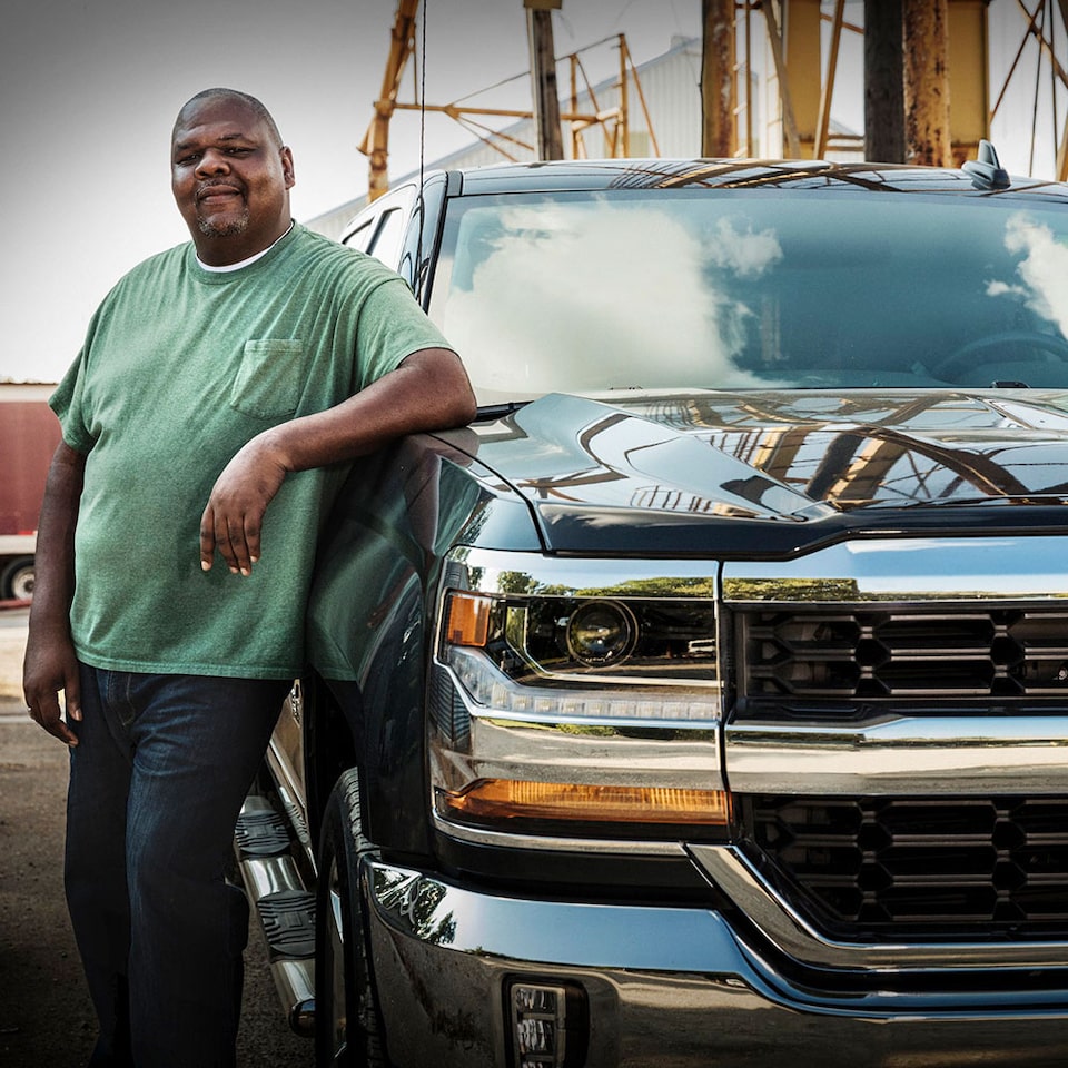 A Man Leaning Against the Hood of His Chevy Silverado Truck