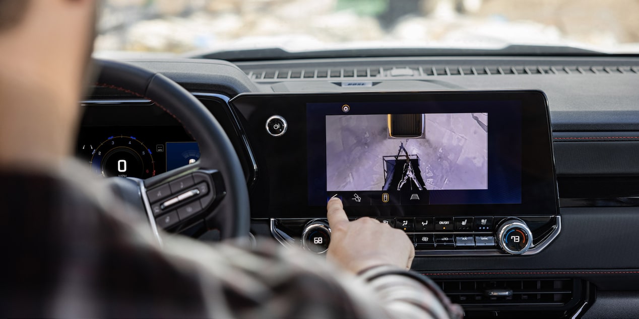 A Driver Interacting with the Dashboard Monitor While Driving in a 2025 Chevy Colorado