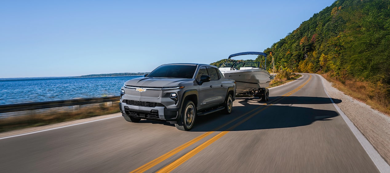 Chevy Silverado EV Towing a Speed Boat Near a Lake