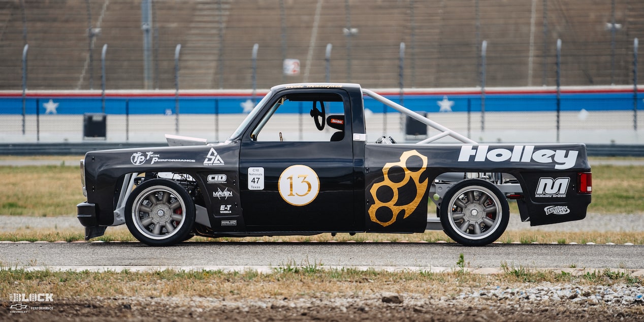 Vista lateral de una camioneta Chevy R10 de 1987 con calcomanías de Racing Autocross sobre una pista